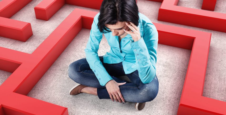 Sad girl sits in a labyrinth with red walls