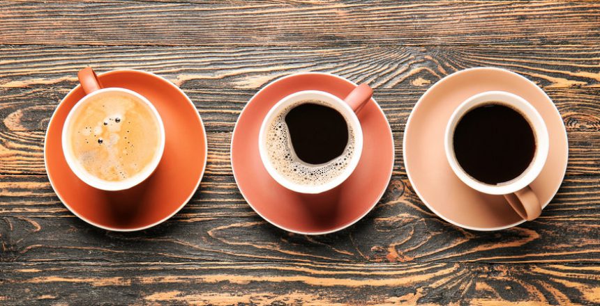 Cups of hot coffee on wooden background