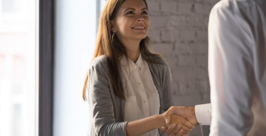 Businessman shake hand of excited female employee greeting with job promotion or employment, male boss handshake happy young woman worker congratulating with success or achievement in office