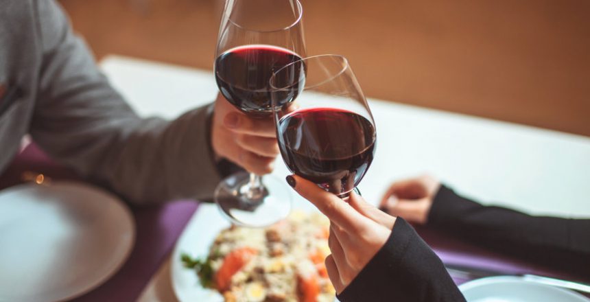 Beautiful young couple with glasses of red wine in luxury restaurant