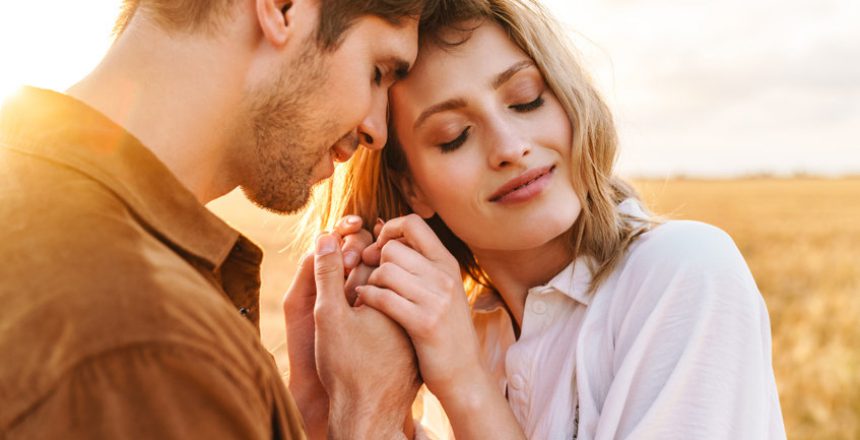 Image of young caucasian beautiful couple hugging together in golden field on countryside